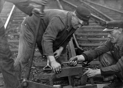 222776 Afbeelding van enkele wegwerkers van de N.S. tijdens het gebruik van de railzaag.